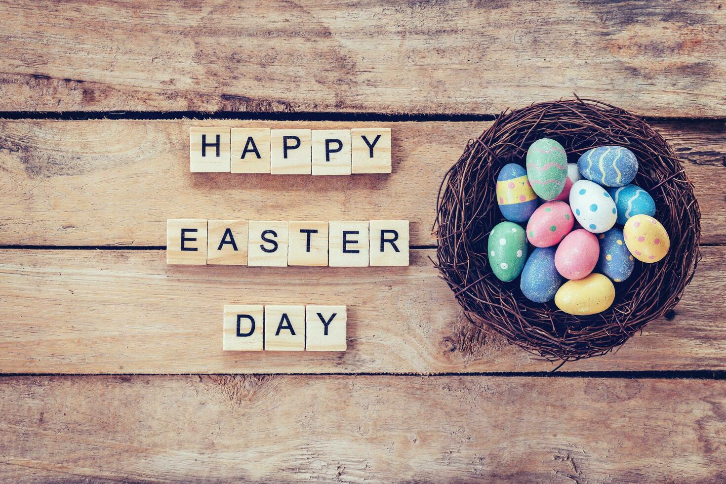 Colorful easter egg in the nest and wood text for Happy Easter Day on wood background with space photo