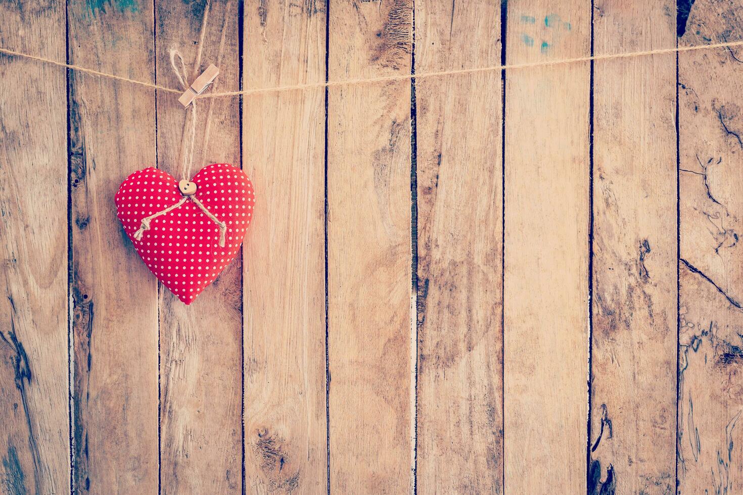 Heart fabric hanging on clothesline and wood background with space. photo