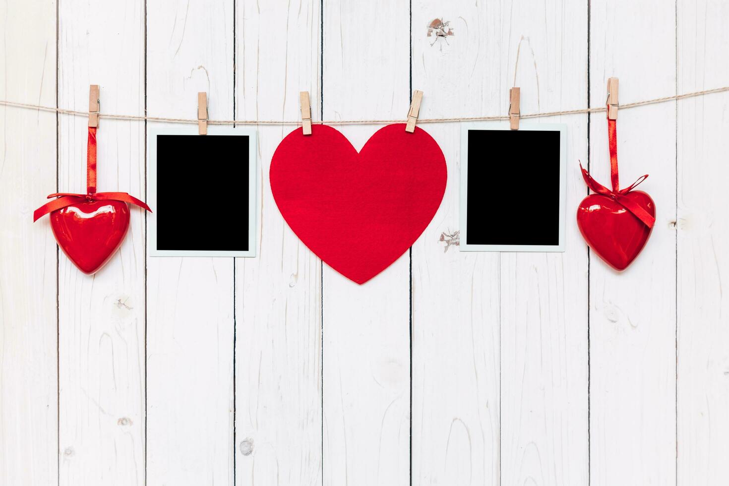 Two photo frame blank and red heart hanging on white wood background with space