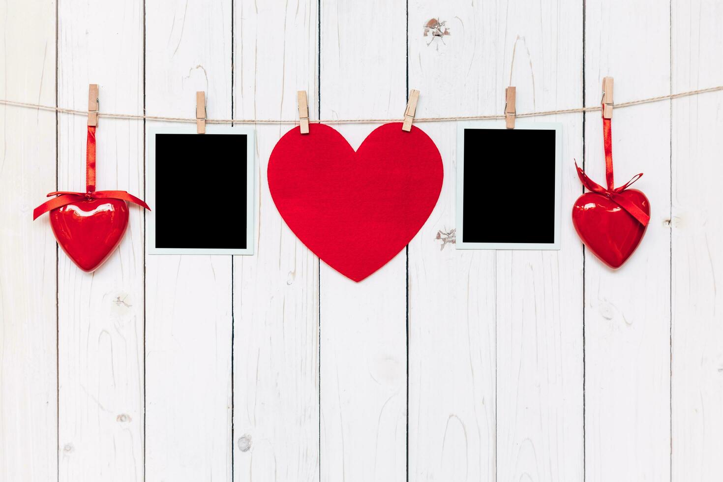 Two photo frame blank and red heart hanging on white wood background with space