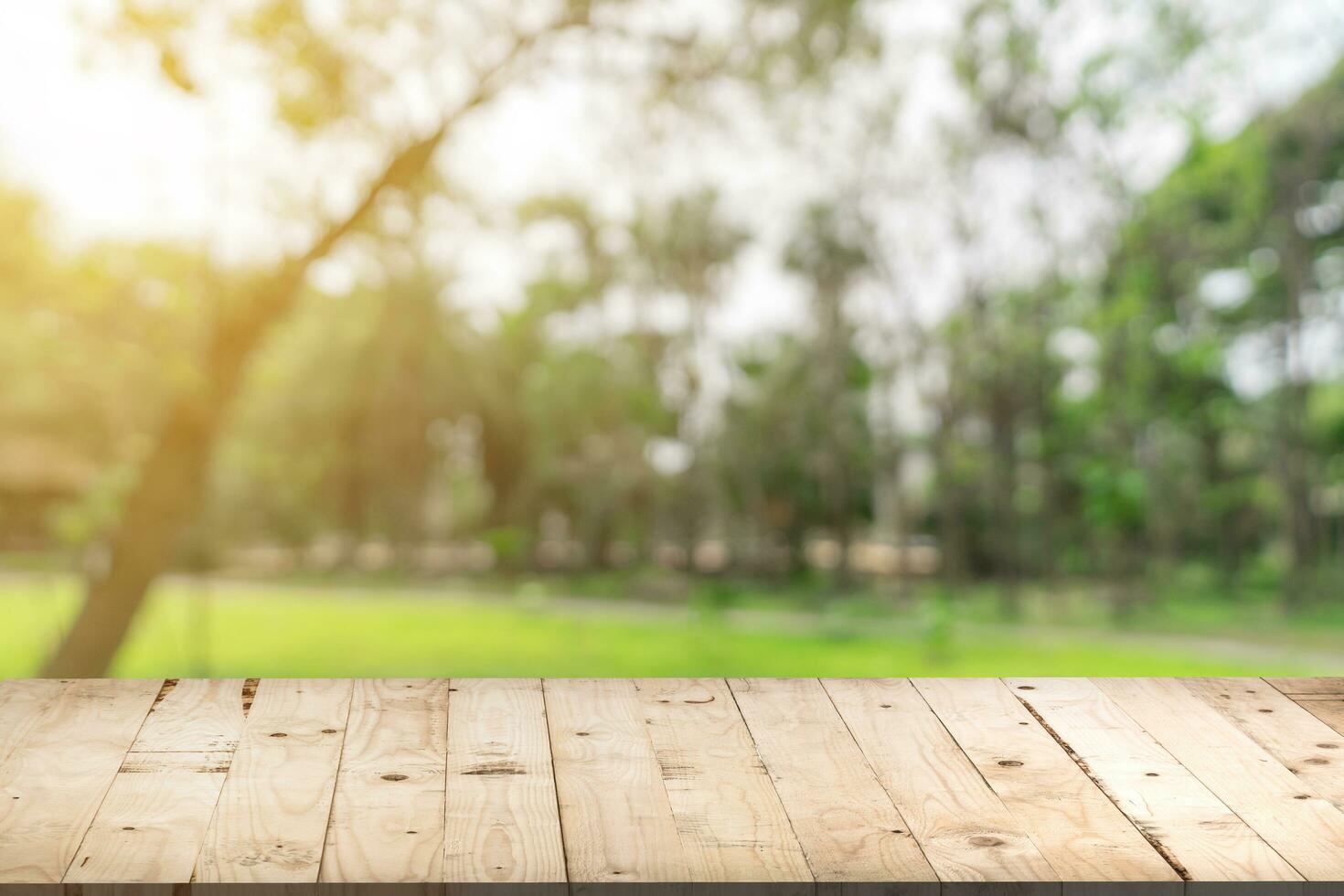 Empty wood table and defocused bokeh and blur background of garden trees in sunlight, display montage for product. photo