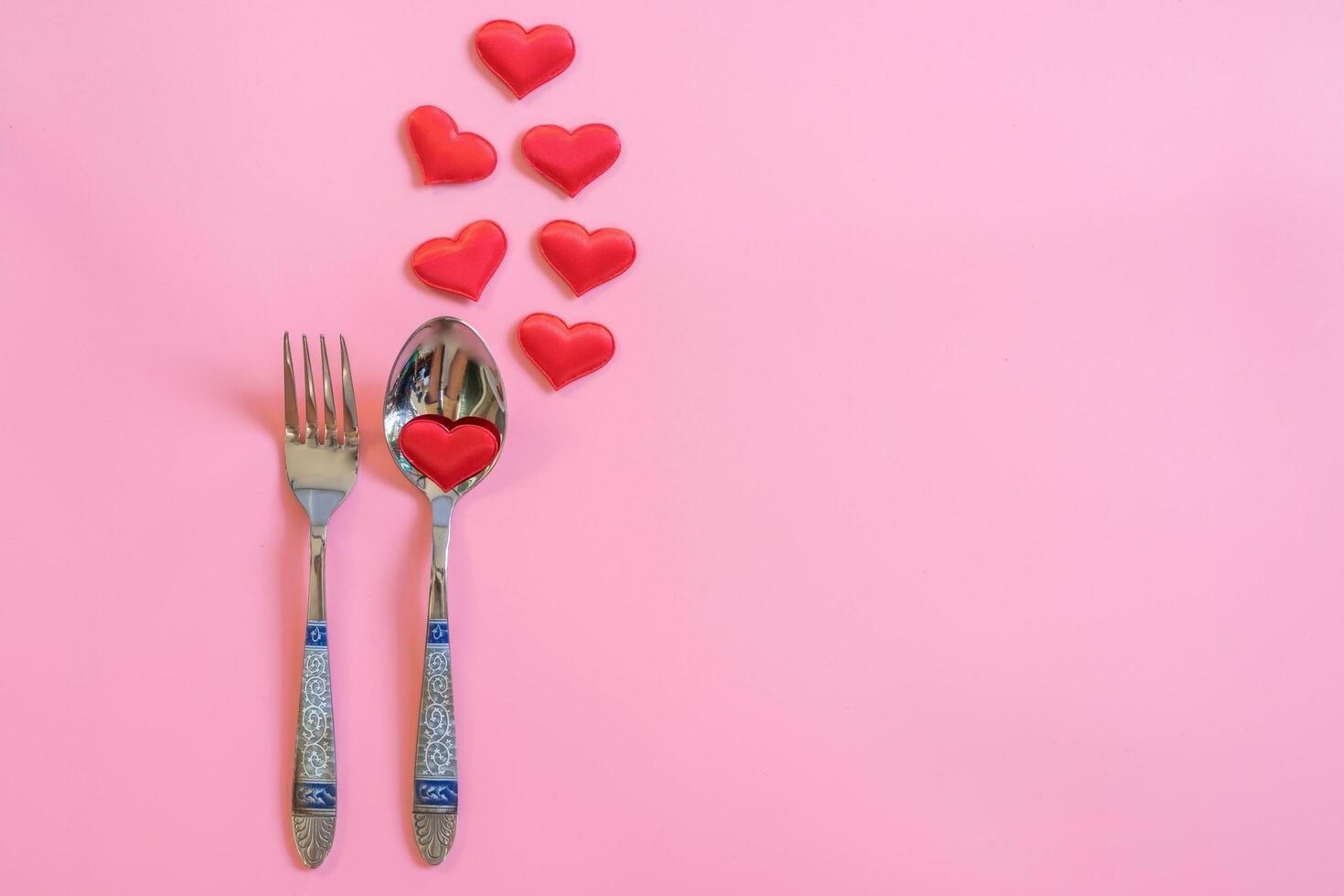 Cutlery set and red heart on pink pastel color with space for text. photo