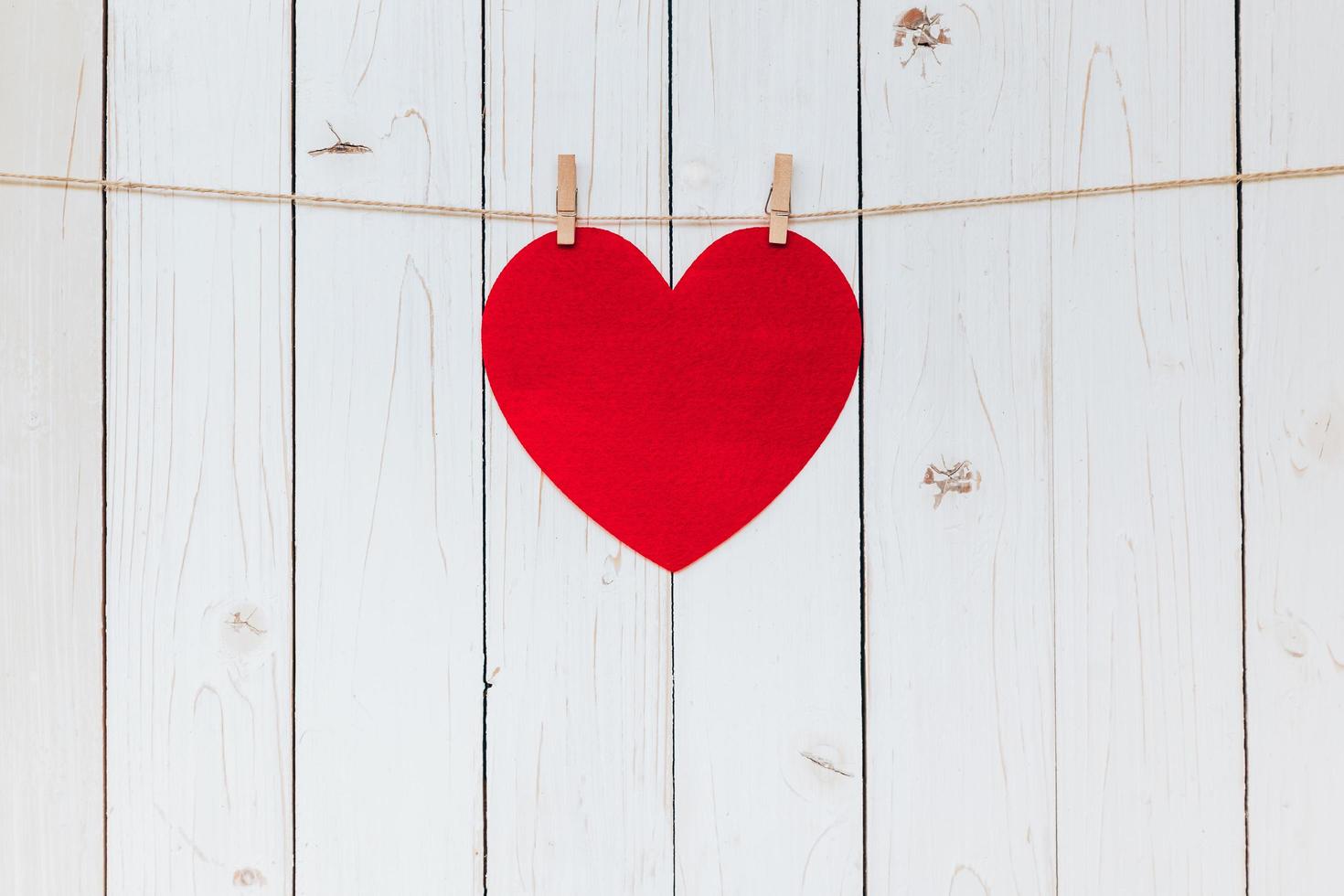 rojo corazón colgando a tendedero en madera blanco antecedentes con espacio. enamorado día. foto