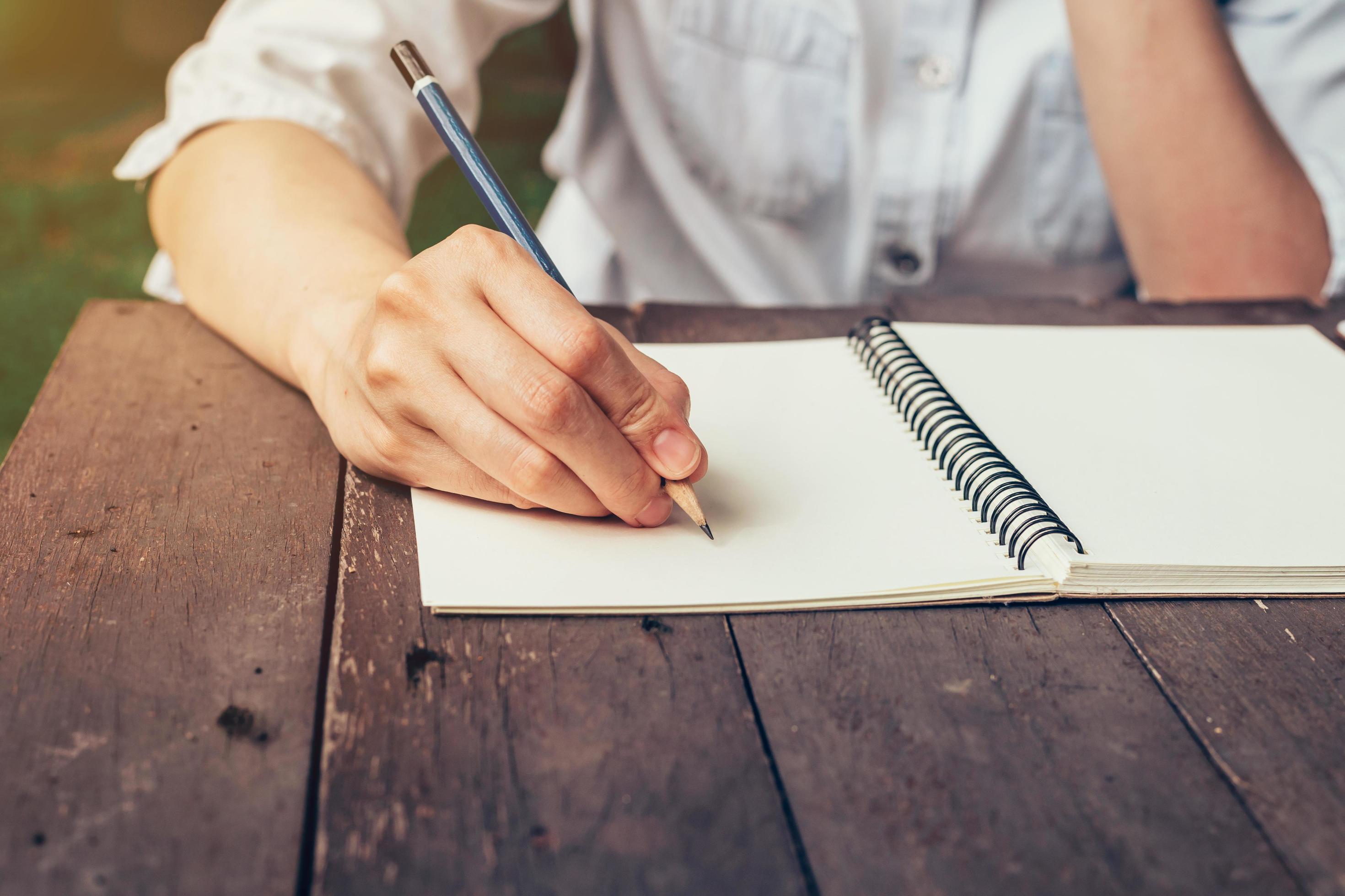 Woman hand writing note pad on wood table in coffee shop. 20670848