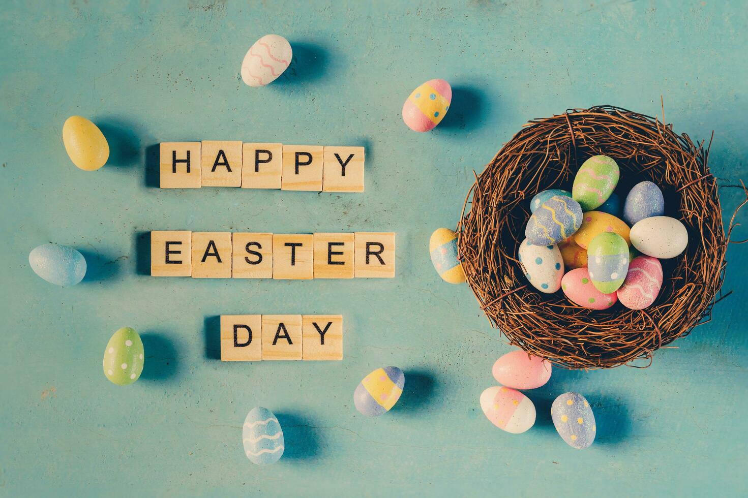Colorful easter egg in the nest and wood text Happy Easter Day on blue pastel color wood background with space. photo