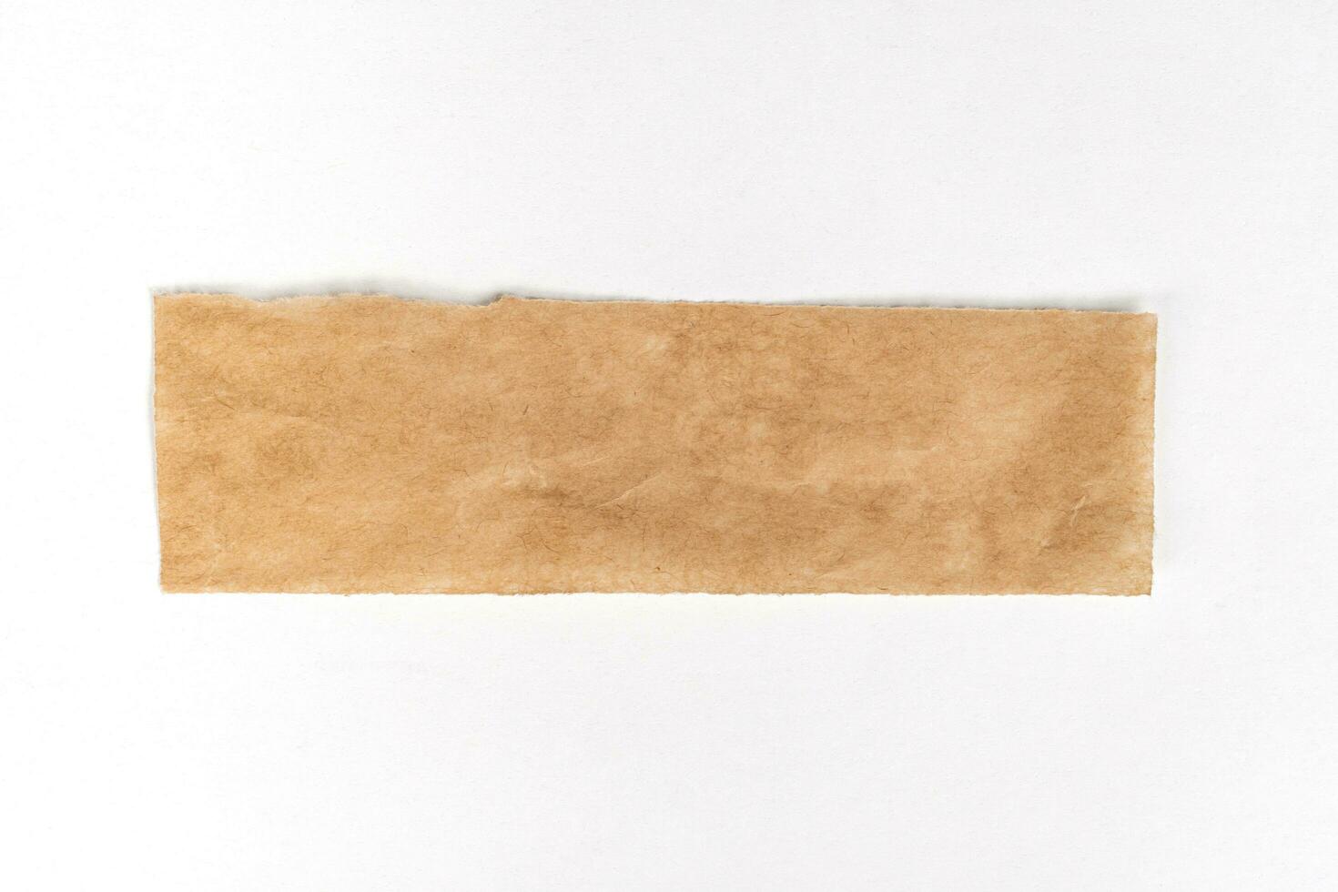 Close up of a ripped piece of brown paper on white background photo