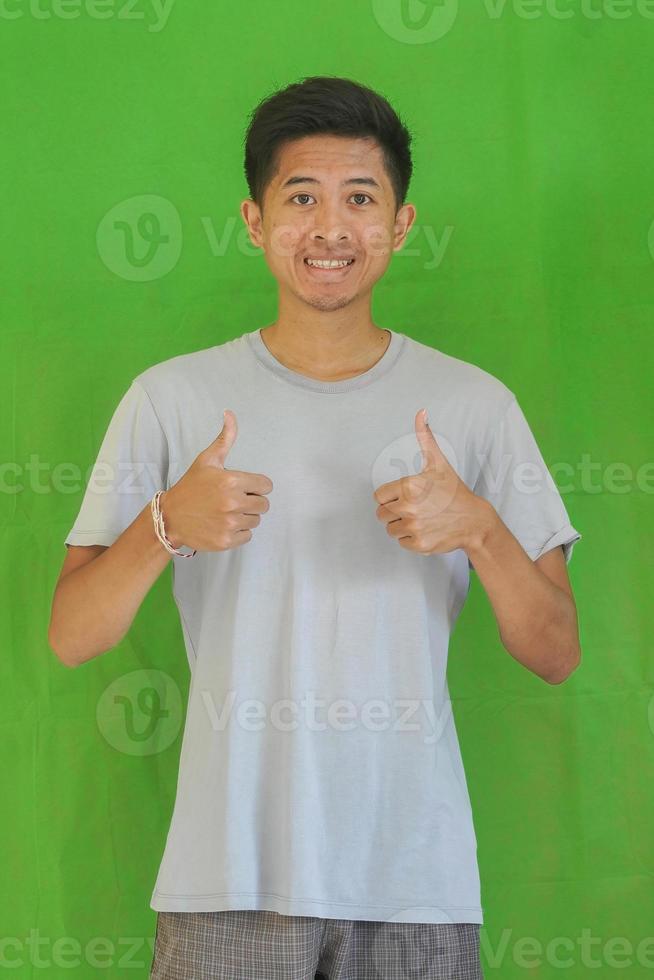 expressive casual Balinese Asian guy model for advertising with green screen studio background photo
