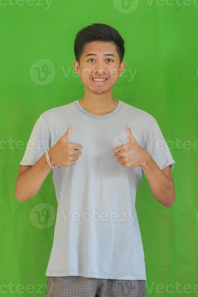 expressive casual Balinese Asian guy model for advertising with green screen studio background photo