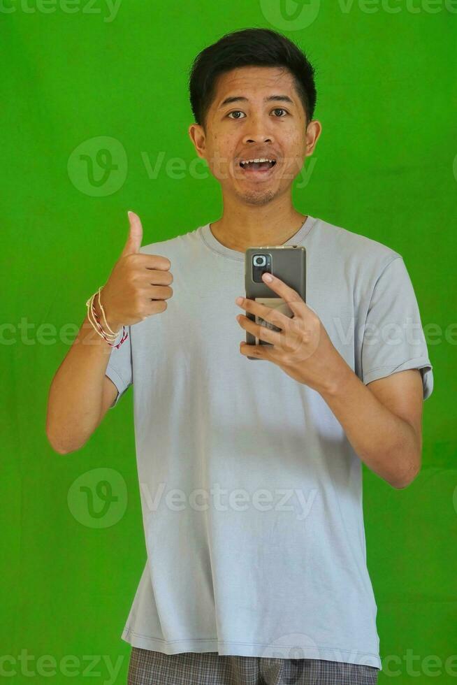 expressive casual Balinese Asian guy model for advertising with green screen studio background photo