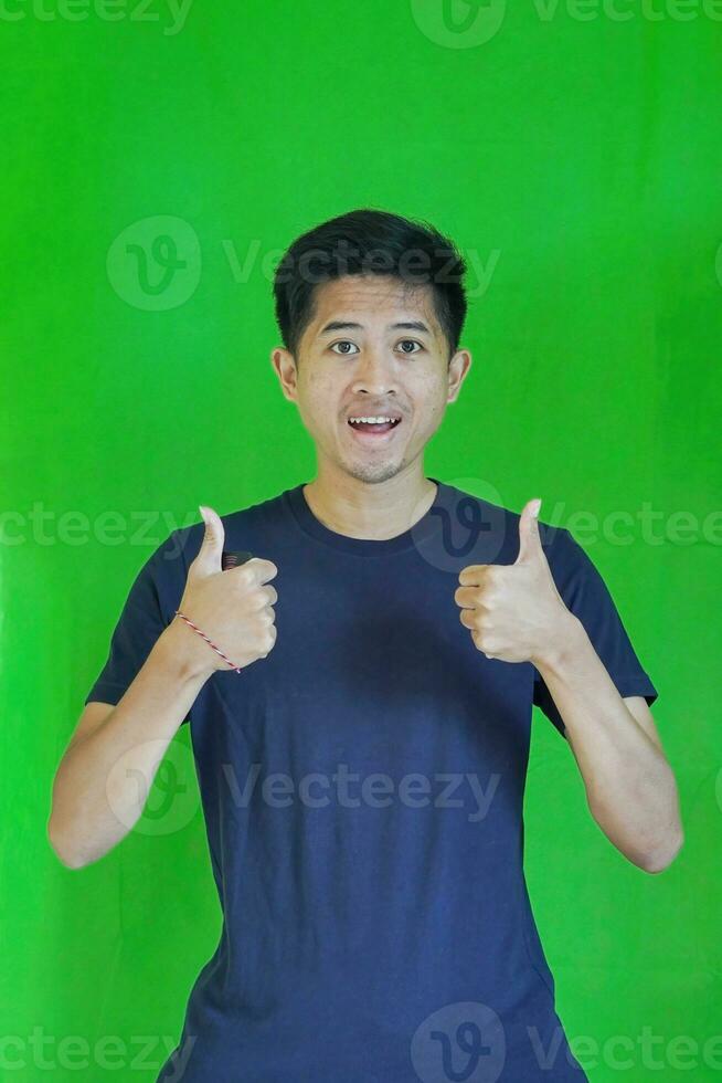 expressive casual Balinese Asian guy model for advertising with green screen studio background photo