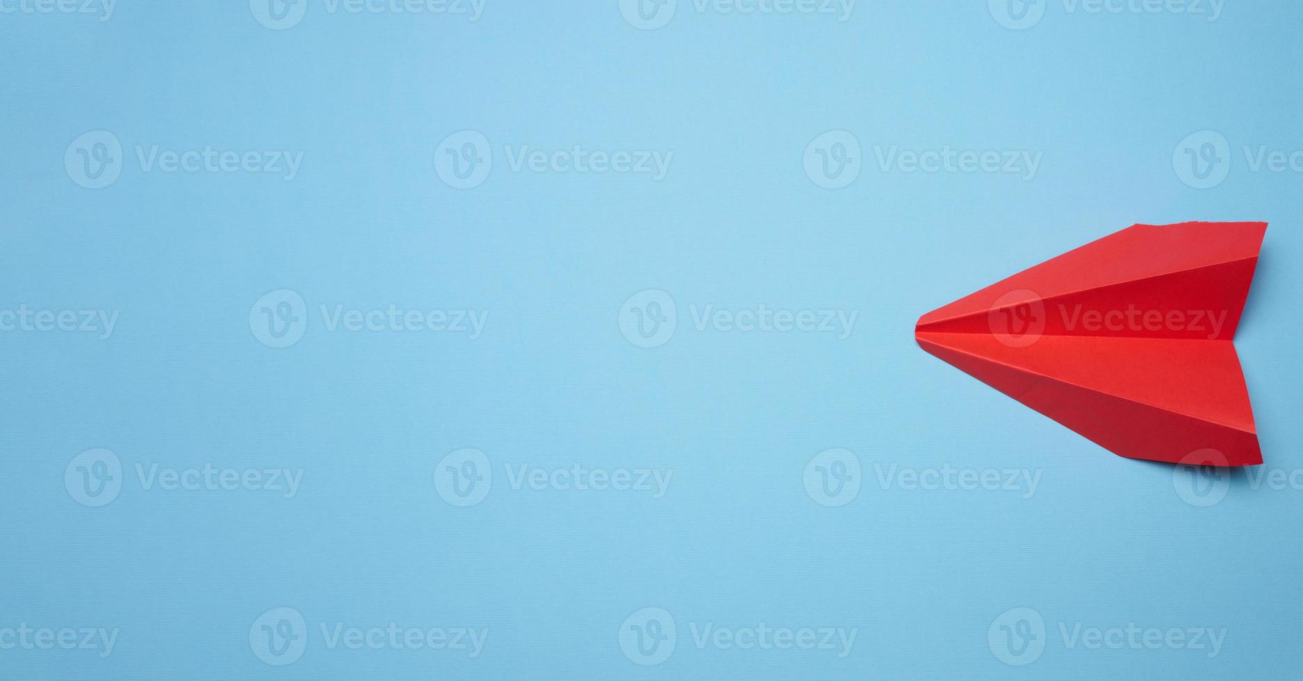 Red paper airplane on a blue background, travel concept, top view photo