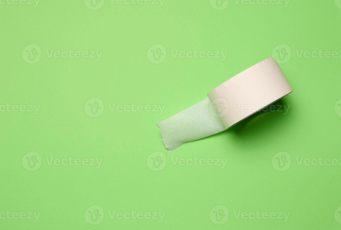 Roll of paper masking tape on green background, top view photo