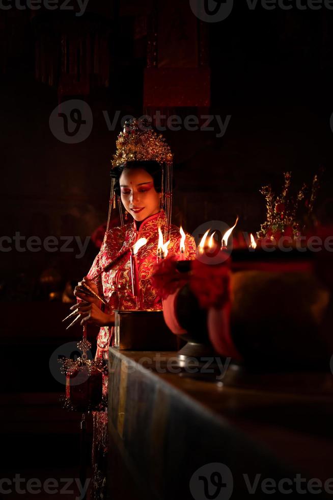 chino mujer hacer deseos, orar, y ligero velas en el ocasión de el anual chino nuevo año festival, en un venerado santuario o templo foto