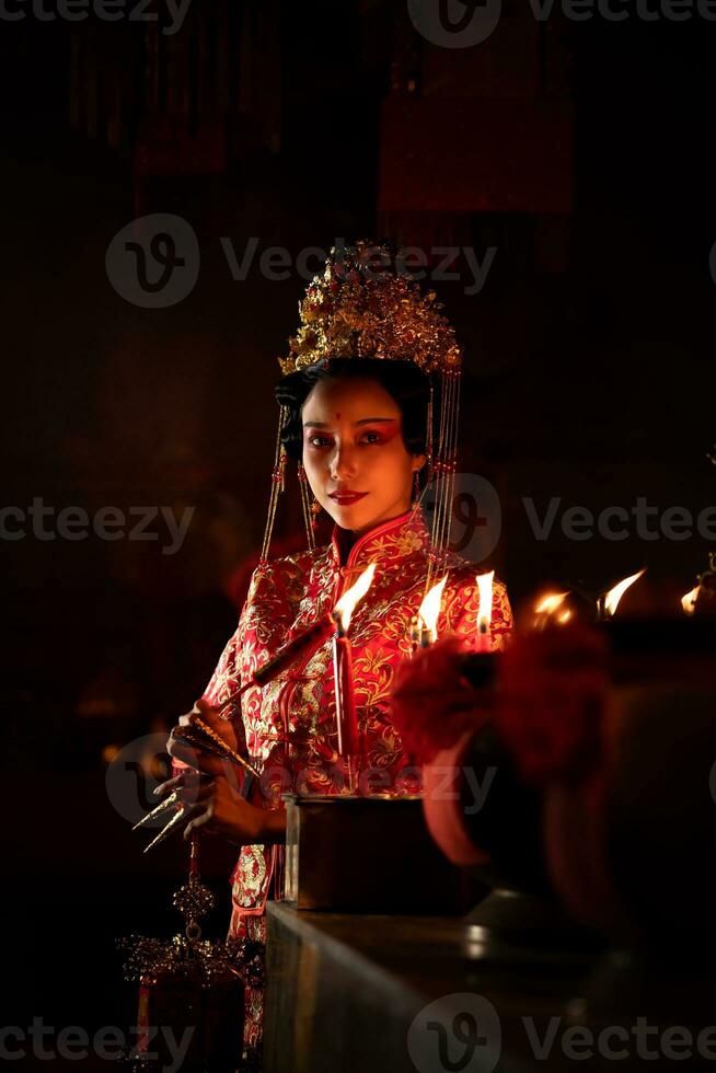 Chinese woman make wishes, pray, and light candles. On the occasion of the annual Chinese New Year festival, in a revered shrine or temple photo