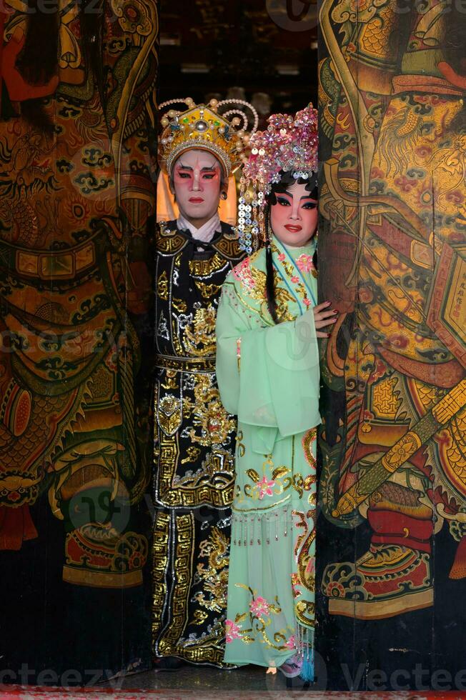 Portrait of male and female opera performers at the entrance to a sacred shrine or temple, praying for blessings on the occasion of the annual Chinese New Year. photo