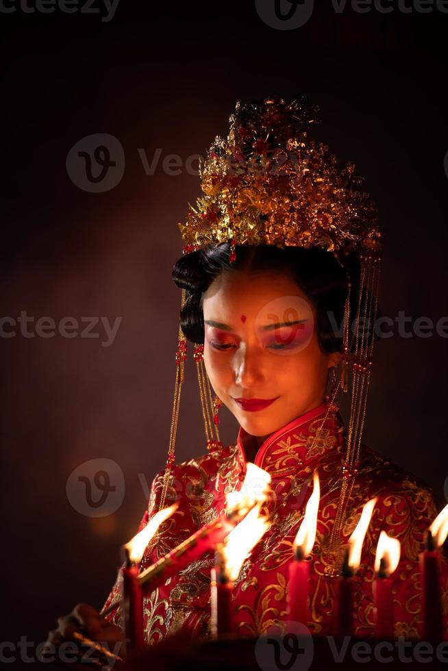 chino mujer hacer deseos, orar, y ligero velas en el ocasión de el anual chino nuevo año festival, en un venerado santuario o templo foto