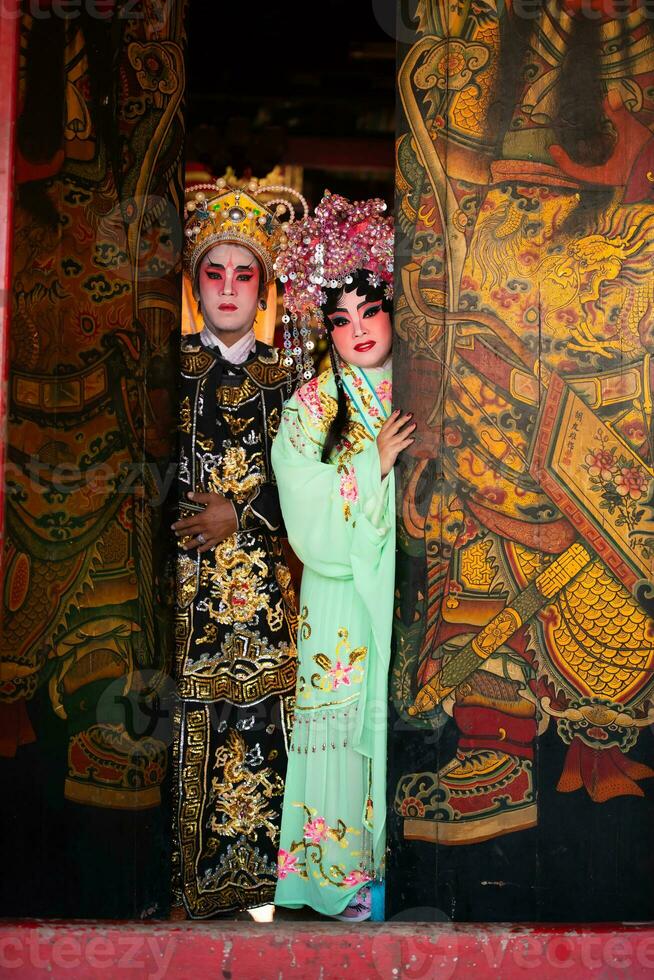 Portrait of male and female opera performers at the entrance to a sacred shrine or temple, praying for blessings on the occasion of the annual Chinese New Year. photo