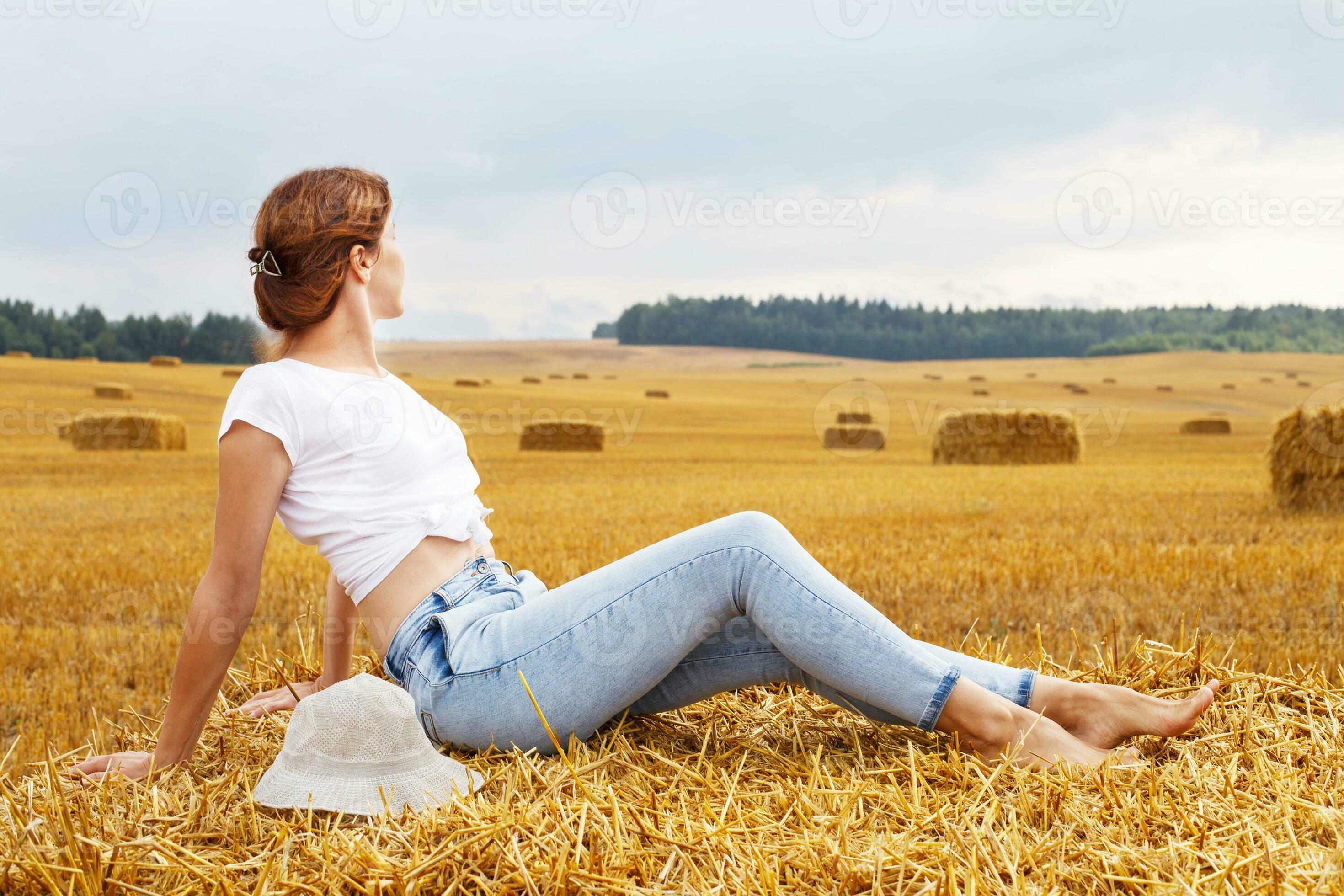 https://static.vecteezy.com/system/resources/previews/020/675/010/large_2x/girl-with-straw-hat-sitting-on-a-haystack-on-a-bale-in-the-agricultural-field-after-harvesting-photo.JPG