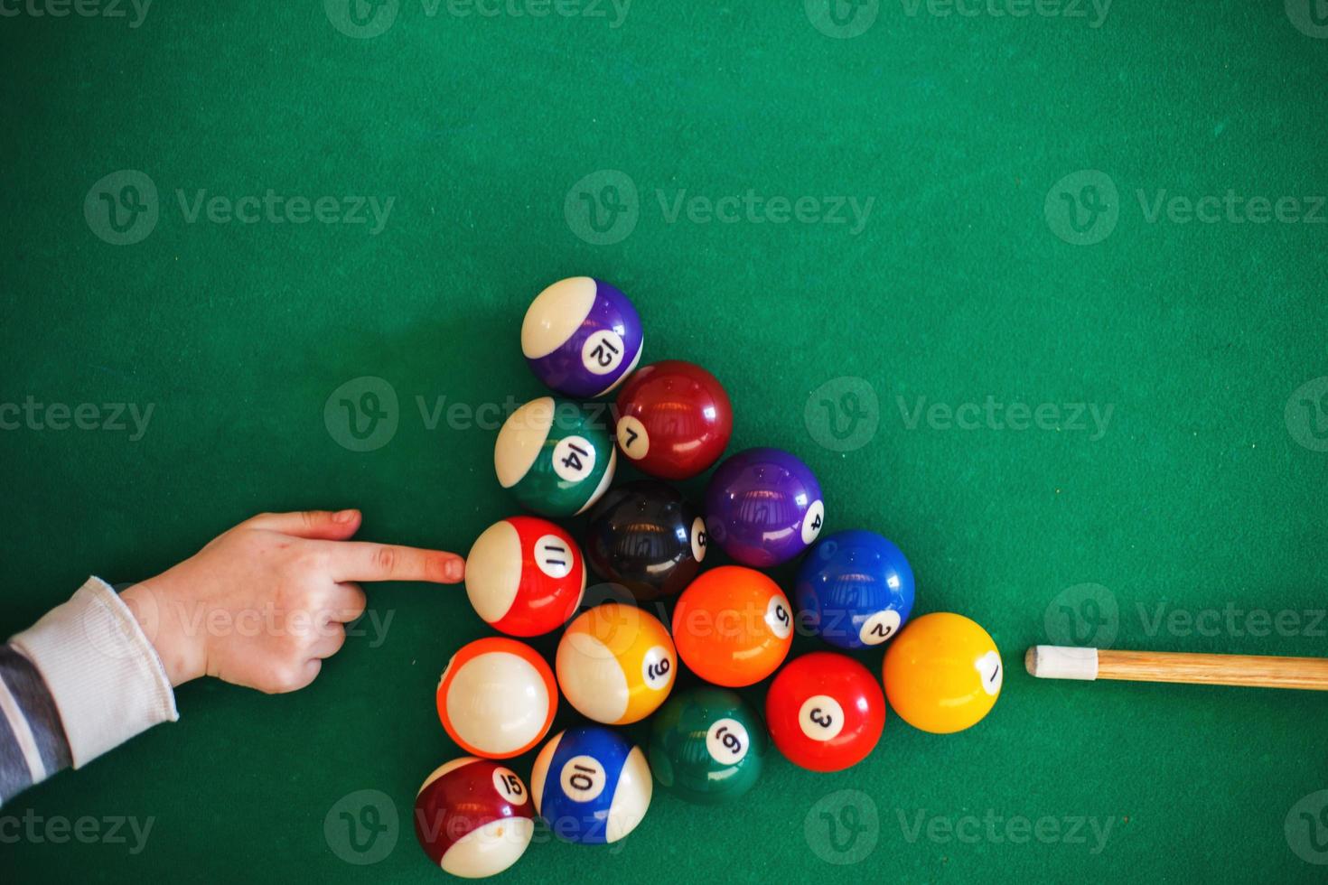 balls on a billiard table in a triangle. child playing billiards photo