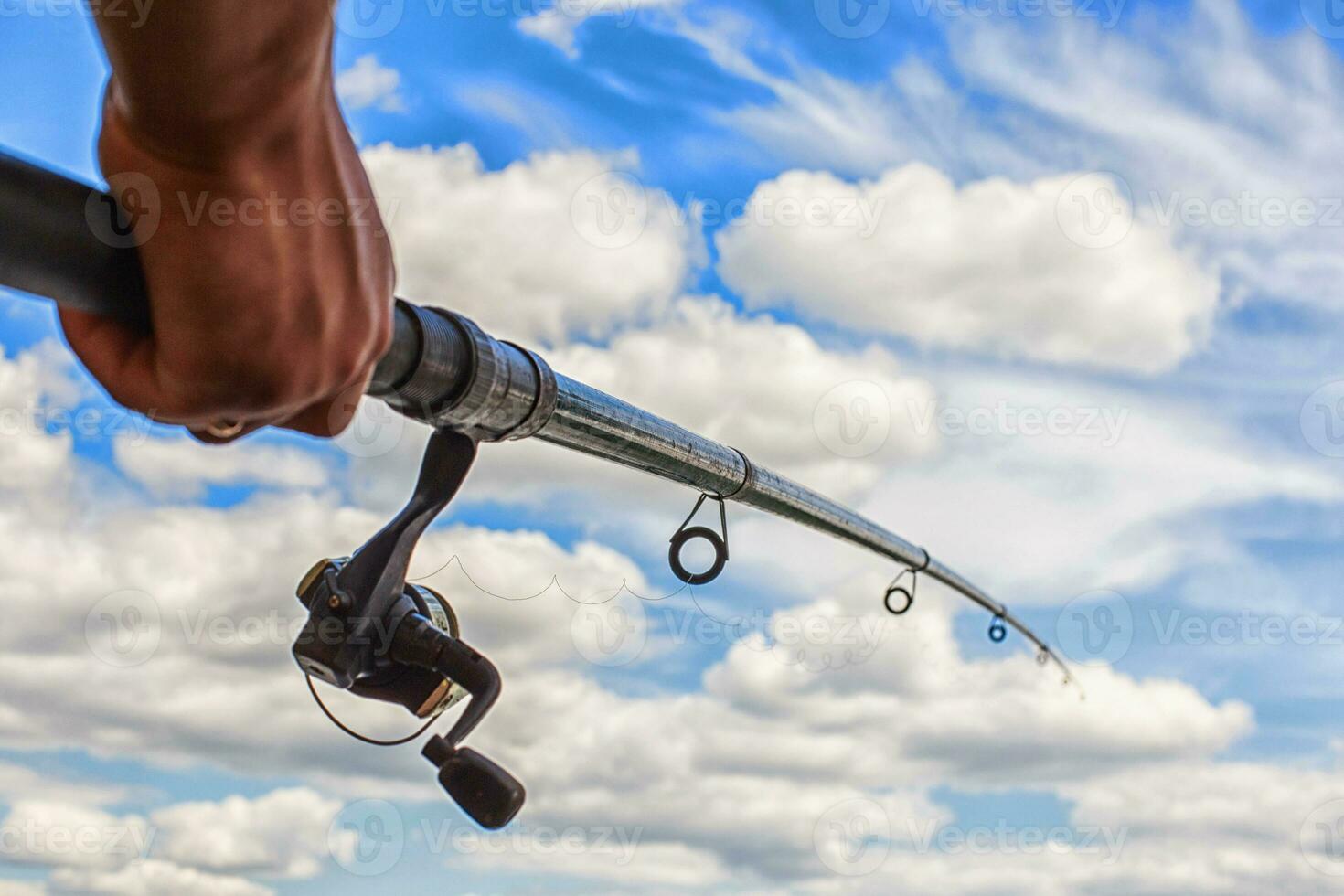 fishing rod on a blue sky background in a man's hand photo