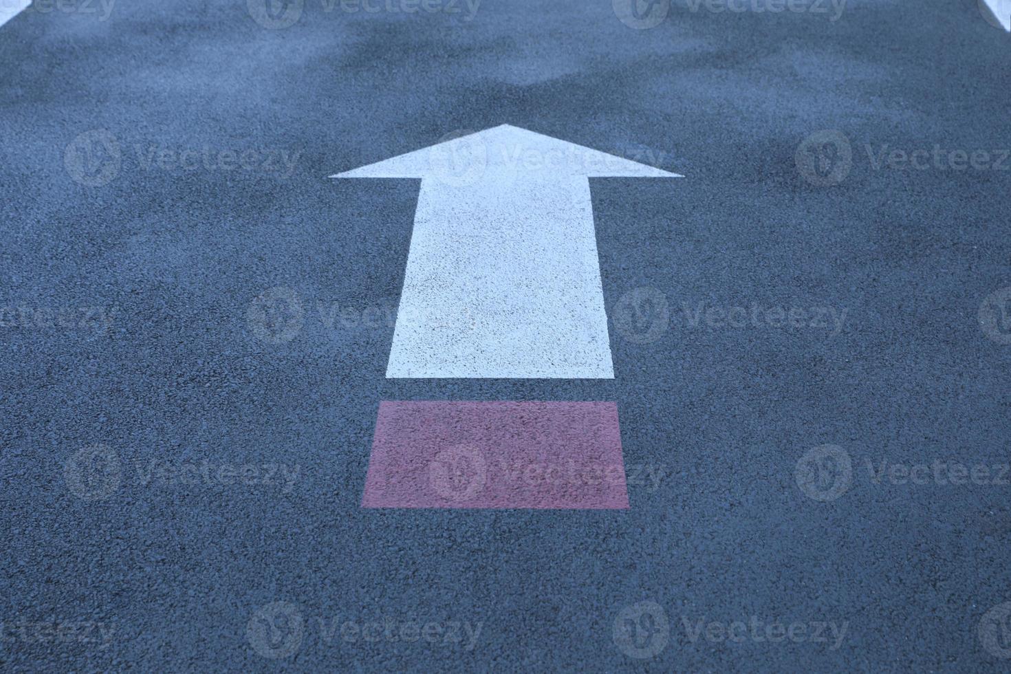 White and red direct arrow on asphalt street. Direction indicator. Signs on the street. photo