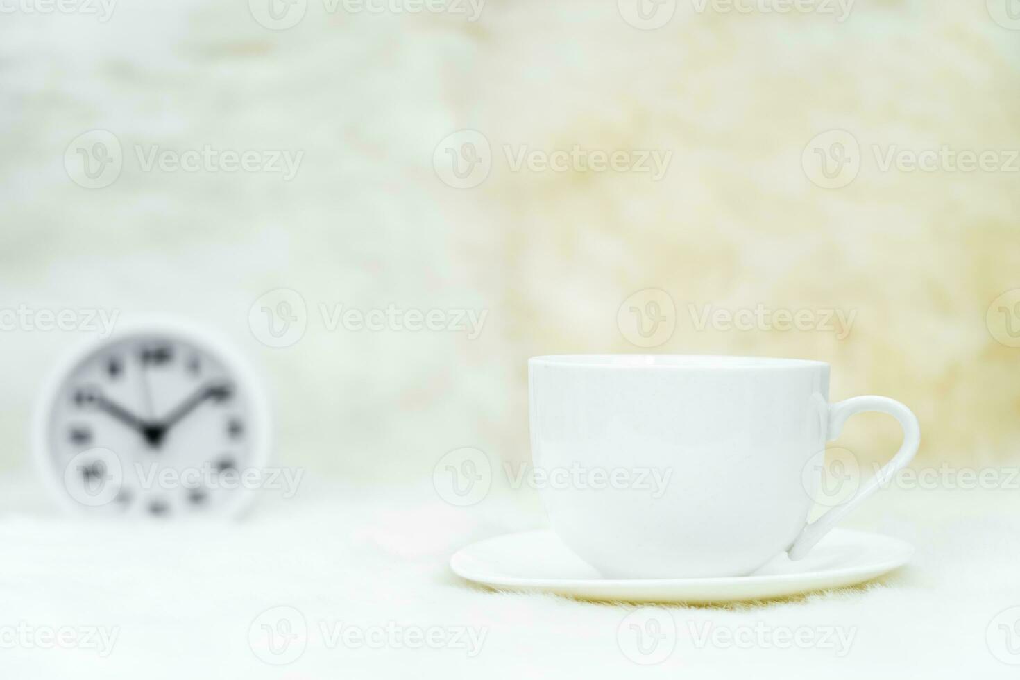 Cup of coffee with alarm clock on table photo