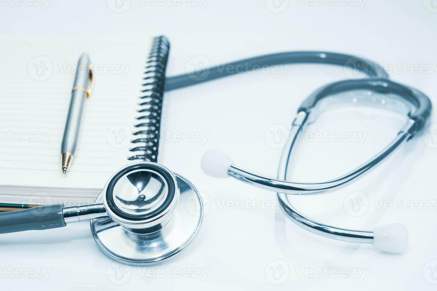 Medical stethoscope for doctor checkup and notepad on table photo