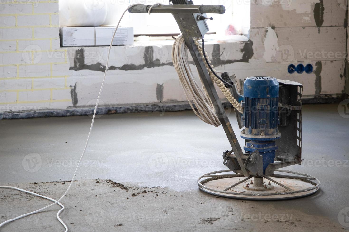 Ramming and grinding of semi-dry floor screed by a machine with a rotating disk for leveling. Construction of a concrete floor in the house, a master with special equipment. photo