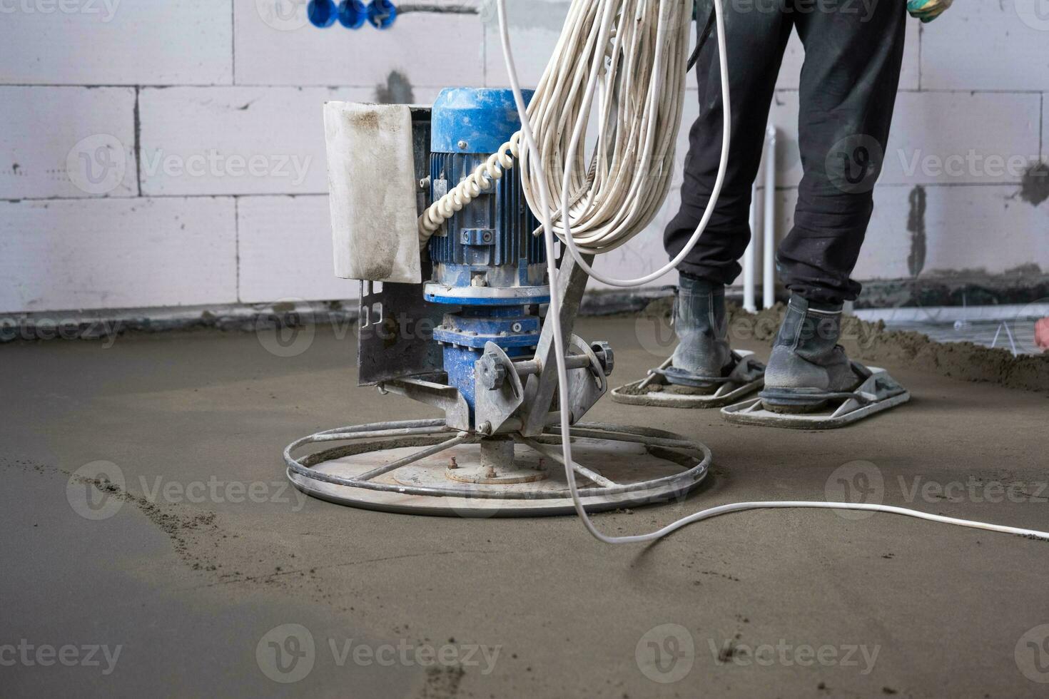 Ramming and grinding of semi-dry floor screed by a machine with a rotating disk for leveling. Construction of a concrete floor in the house, a master with special equipment. photo