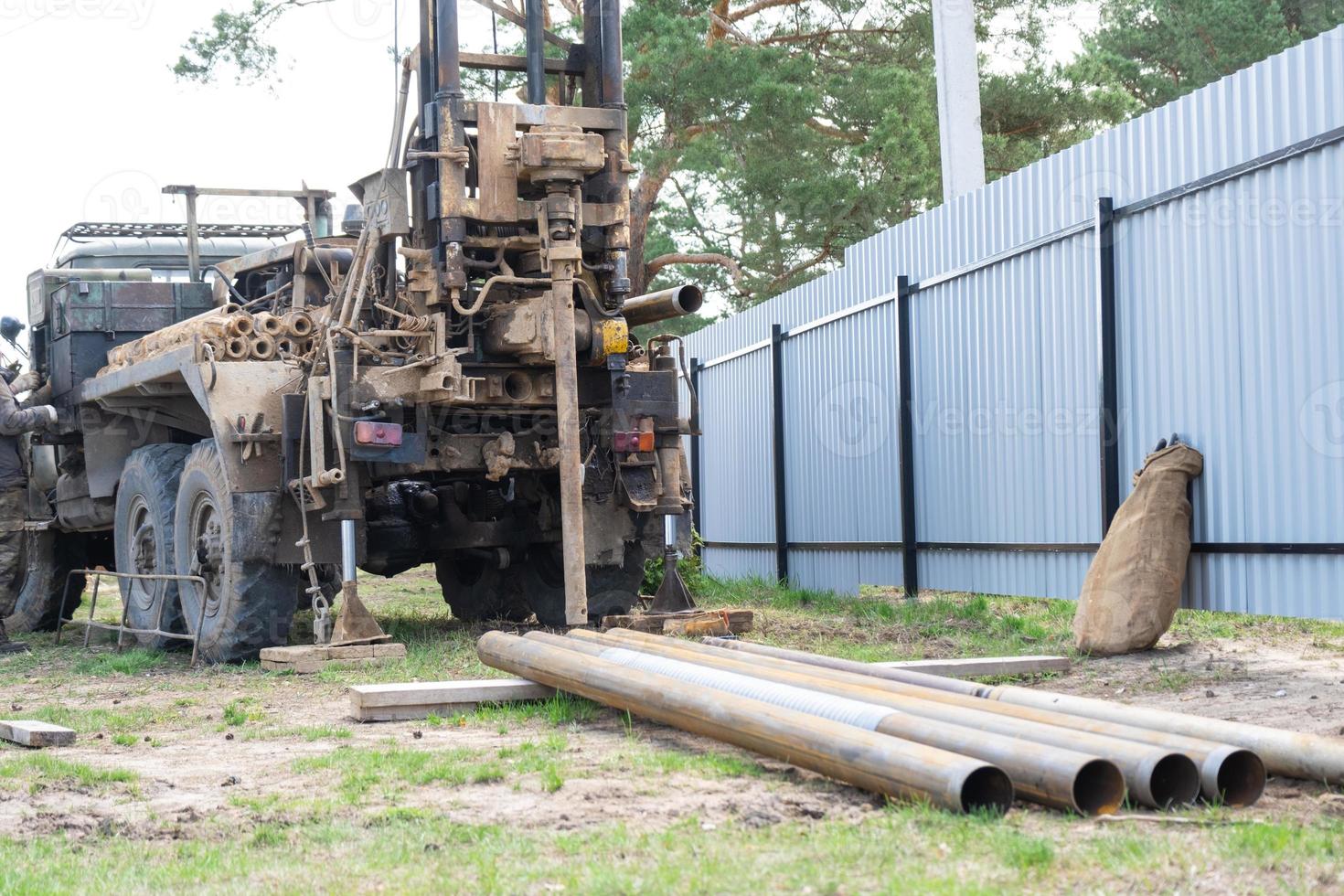 Drilling rig on zil car are drilling artesian well for water in ground. Insertion of metal casing pipe into ground, installation of individual drinking supply photo