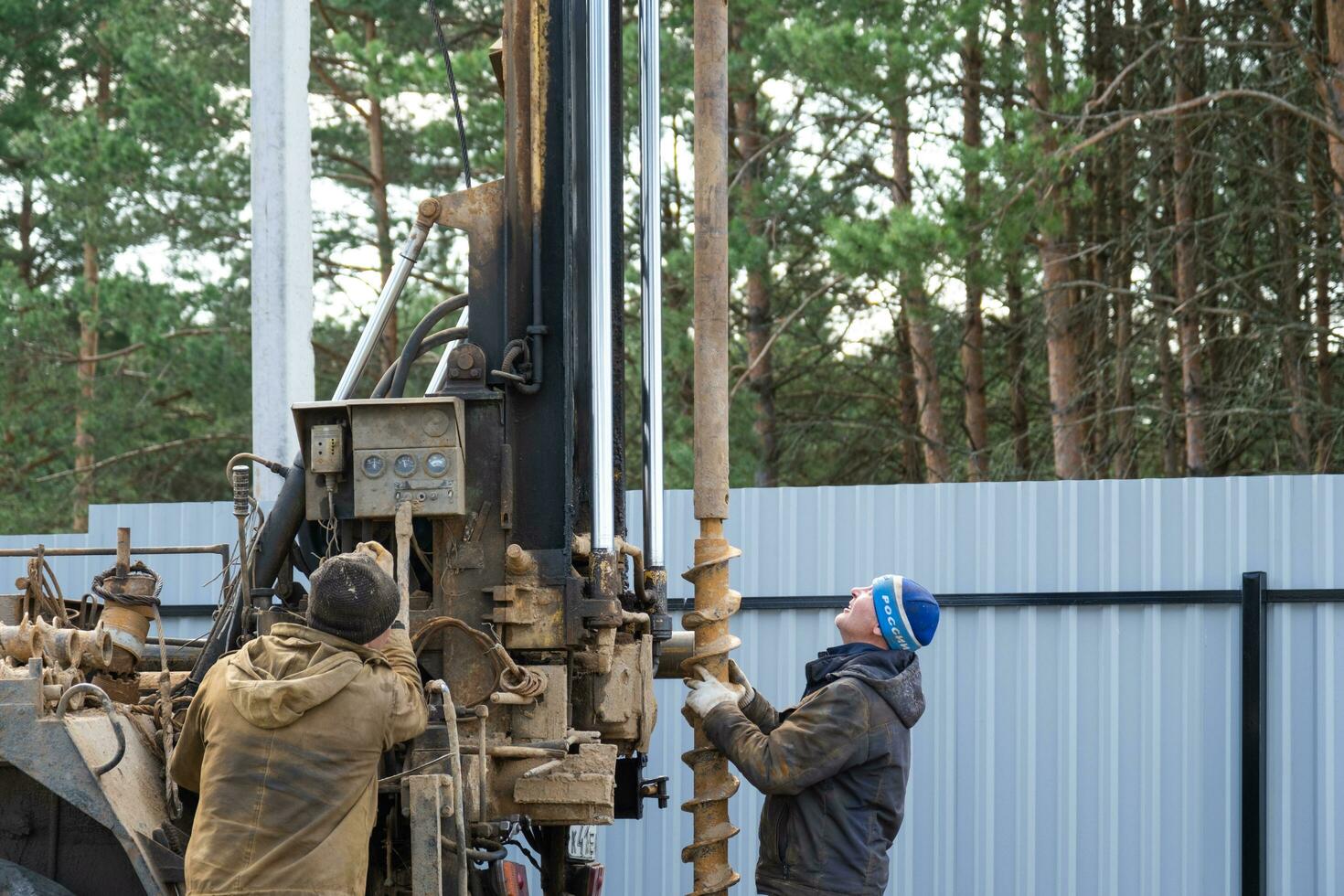 equipo de trabajadores con perforación plataforma en coche son perforación artesiano bien para agua en suelo. inserción de metal caja tubo dentro suelo, instalación de individual Bebiendo suministrar, junio 28, 2022, Rusia, foto