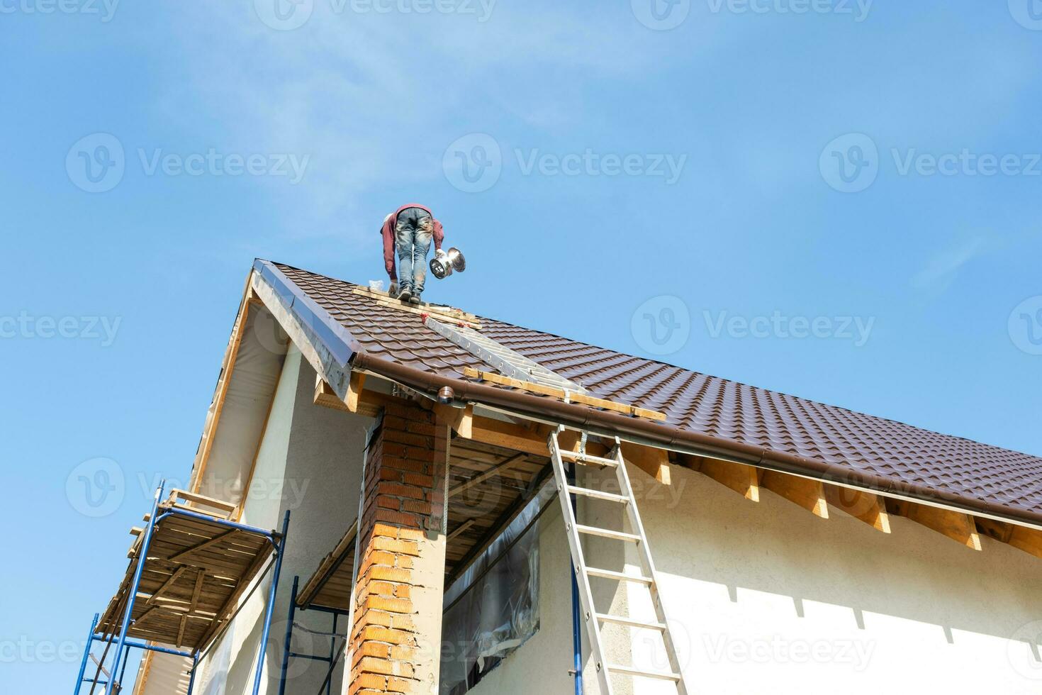 The master for the installation of ventilation pipes and the installation of the chimney of the furnace works on the roof of the house photo