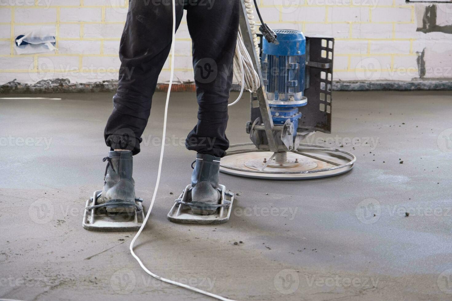 Ramming and grinding of semi-dry floor screed by a machine with a rotating disk for leveling. Construction of a concrete floor in the house, a master with special equipment. photo