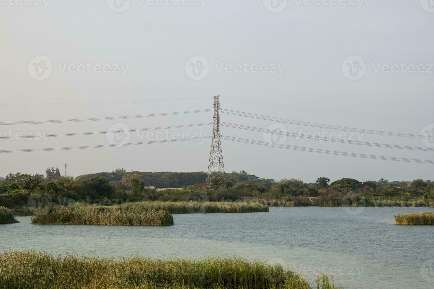High Voltage Poles - Long-term lakeside high-voltage poles are being built by experienced engineers to provide people with electricity and consumer services. photo