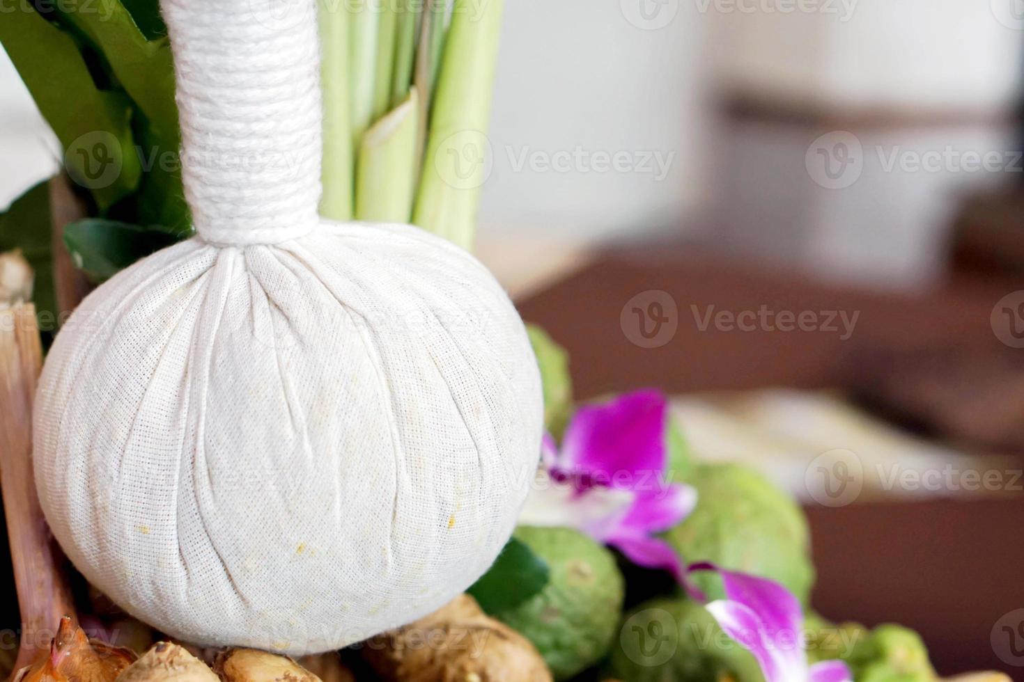 Closeup herbal spa ball and Thai herbs for treatment or massage in blurry Thai spa room background photo