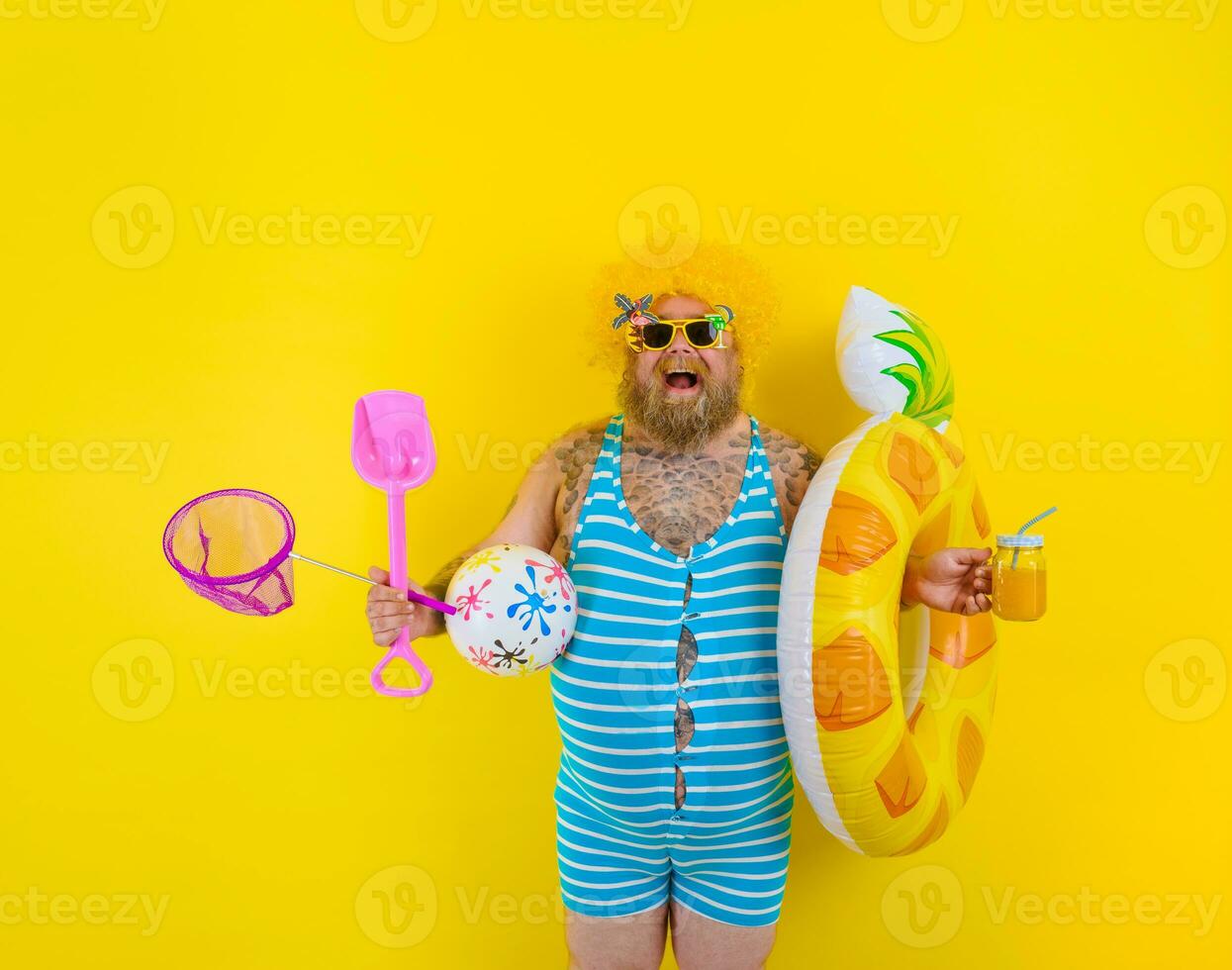 Fat amazed man with wig in head is ready to swim with a donut lifesaver photo