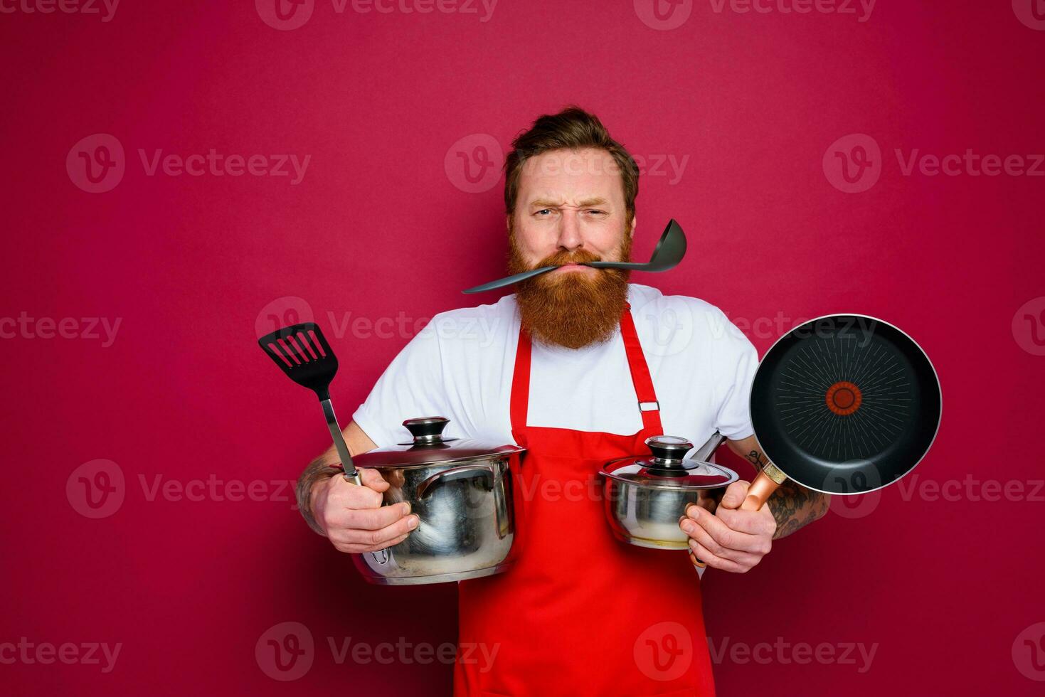 unhappy chef with beard and red apron is ready to cook photo