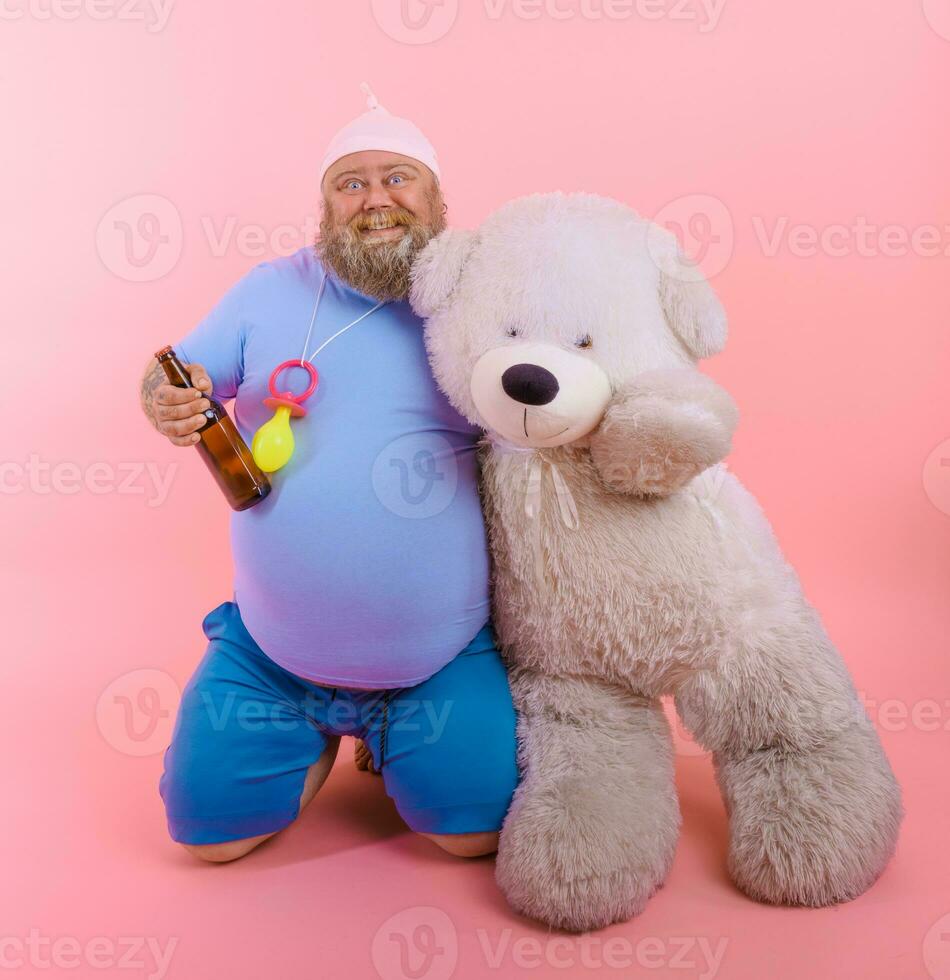 Fat happy man acts like a happy baby but drinks beer photo