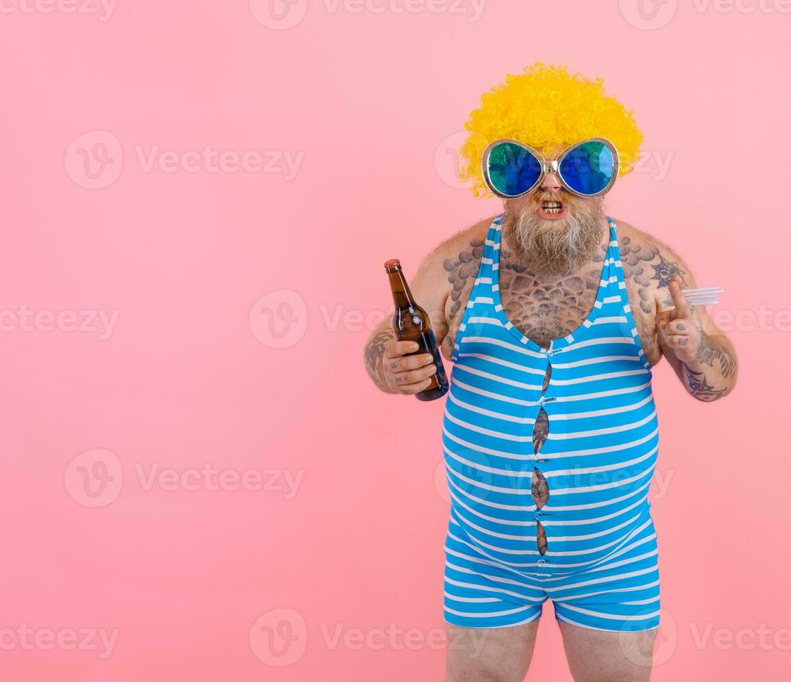 Fat man with beard and wig smokes cigarettes and drinks beer photo