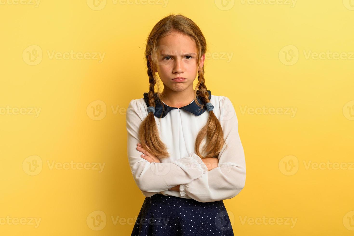 Young girl is unhappy and angry about something. yellow background photo