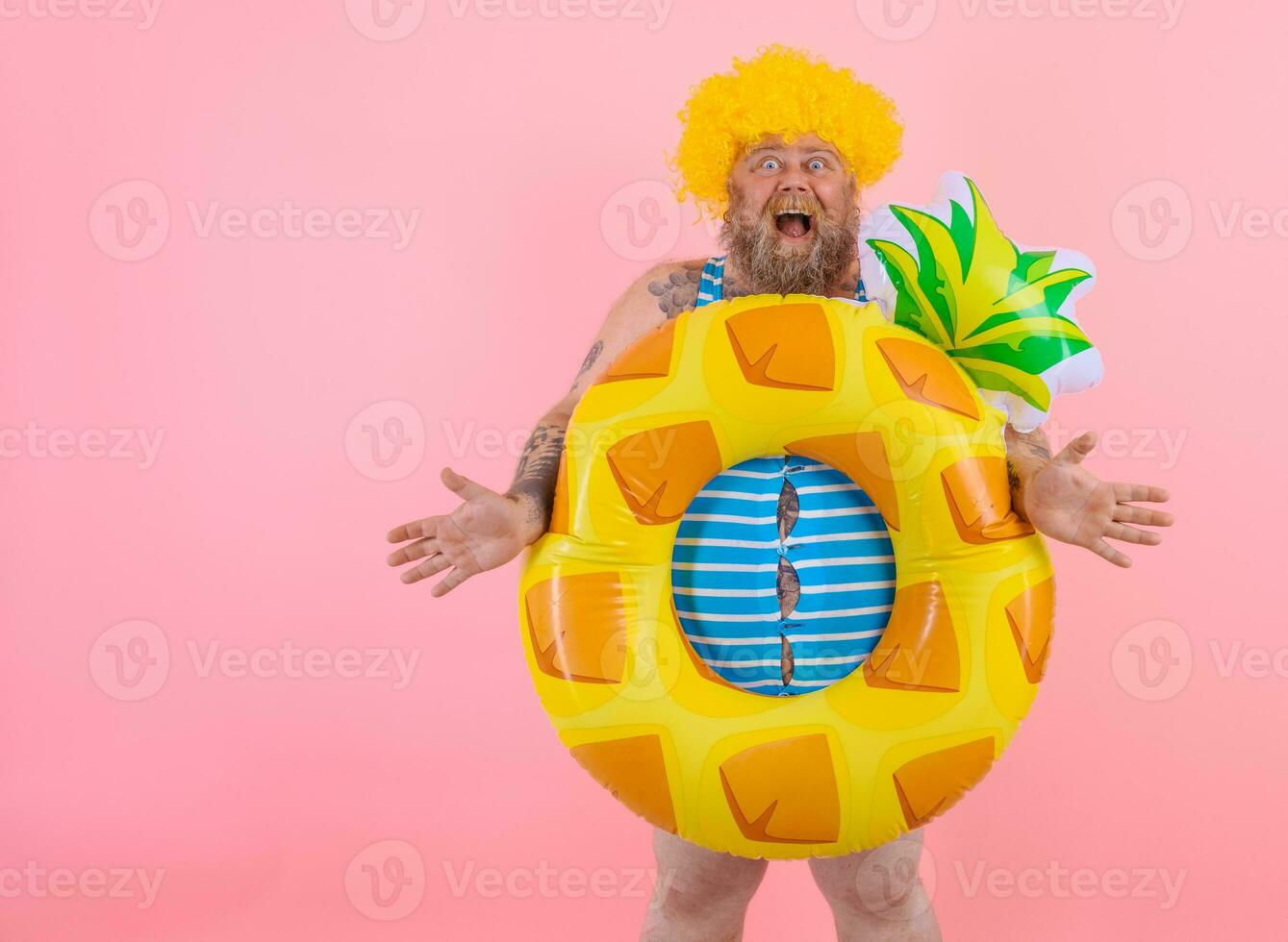 Fat amazed man with wig in head is ready to swim with a donut lifesaver photo