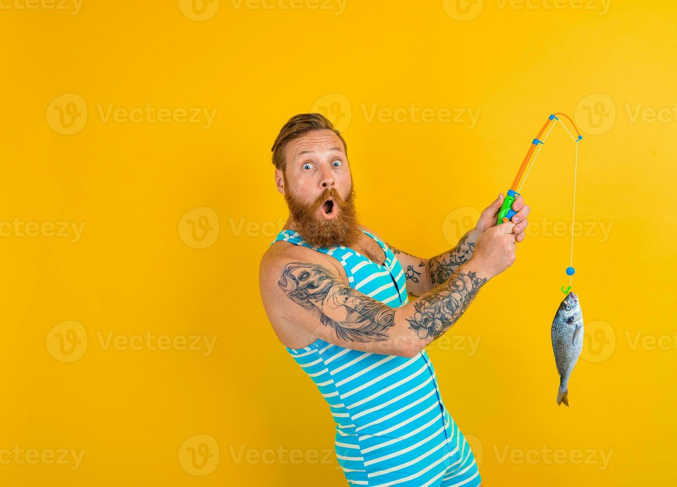 man with beard and swimsuit caught a fish photo