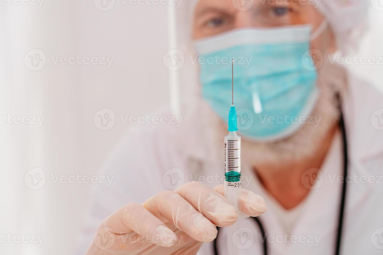 Doctor with mask and syringe is ready to administer the vaccine against covid 19 photo