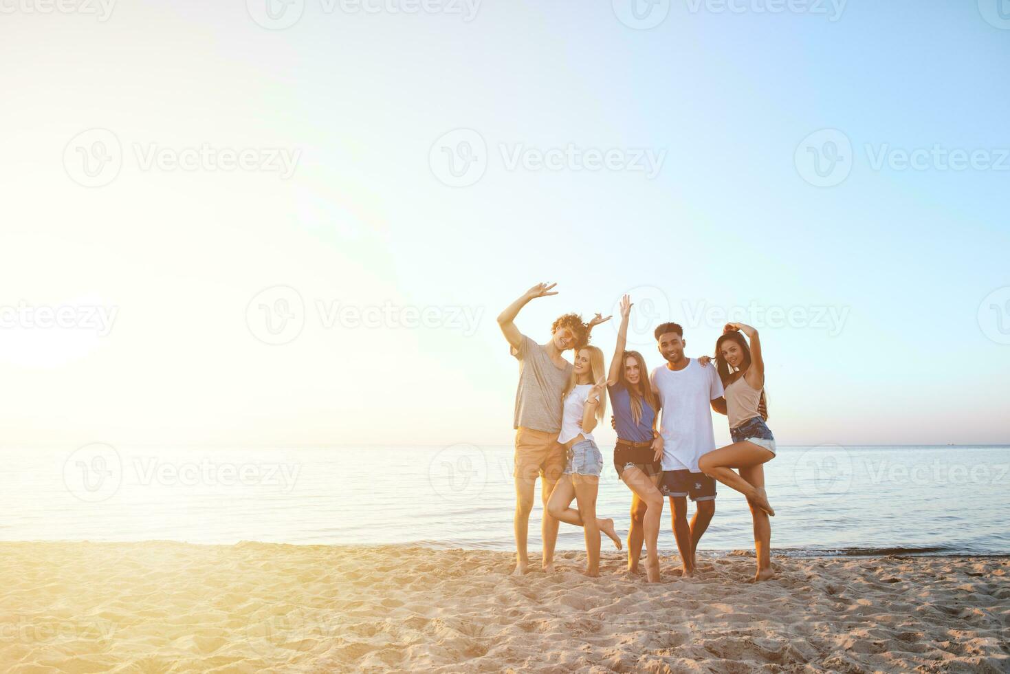 grupo de contento amigos teniendo divertido a Oceano playa a amanecer foto