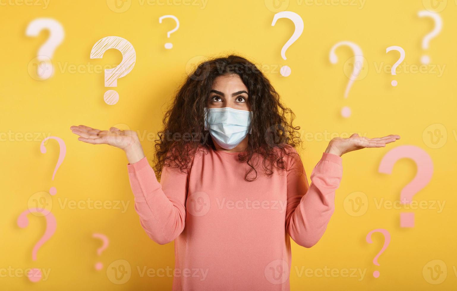 Girl with face mask has a lot of question about covid 19. Yellow background photo