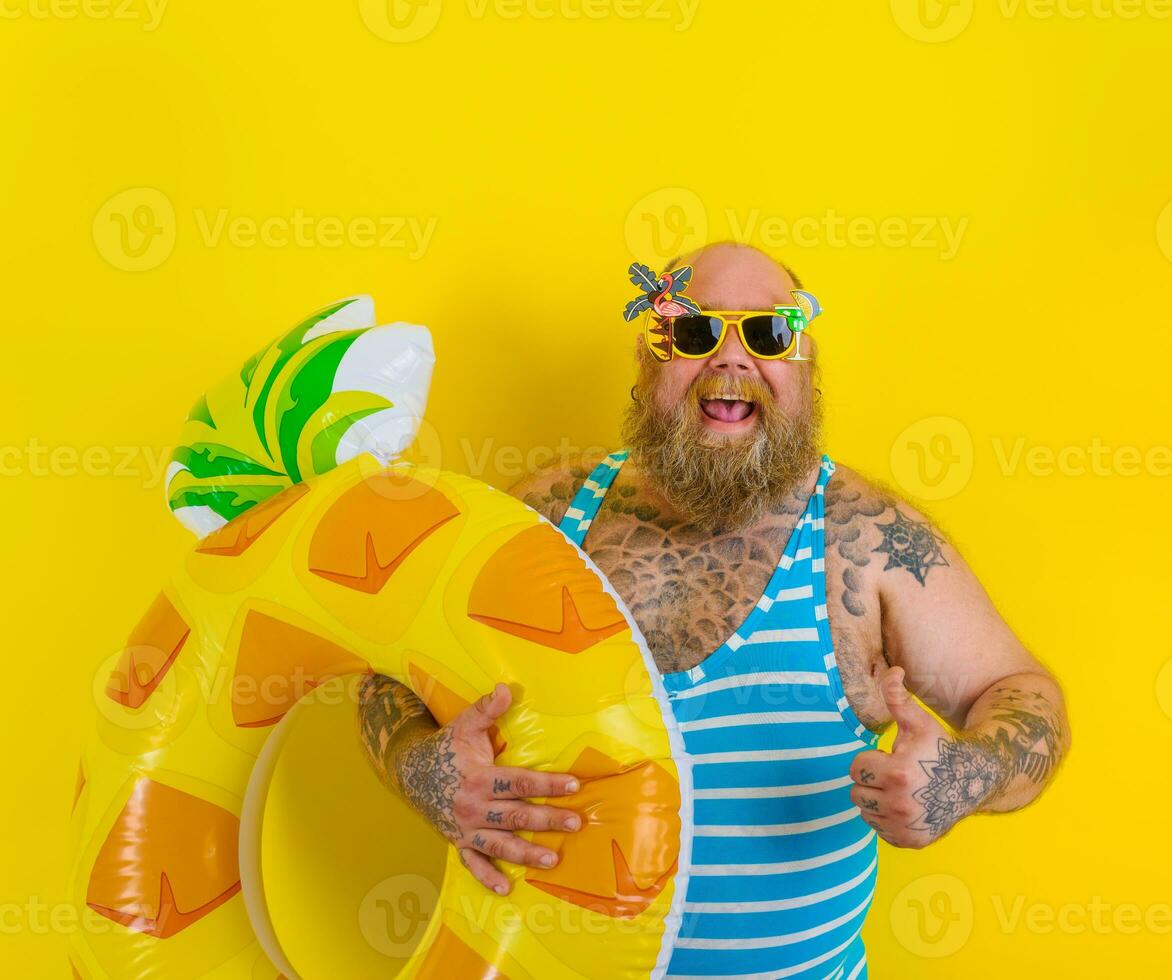 Fat happy man with wig in head is ready to swim with a donut lifesaver photo