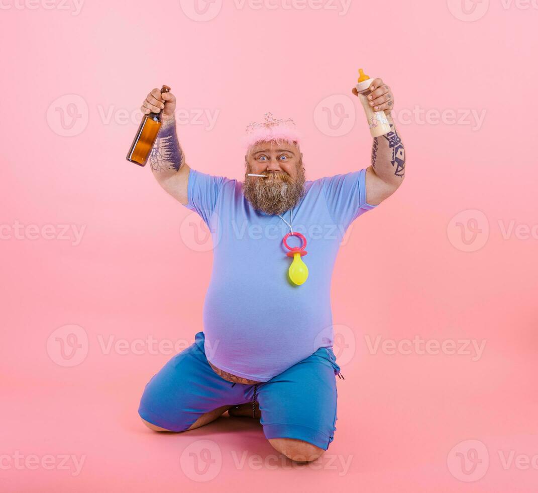 Fat happy man acts like a happy baby but drinks beer photo