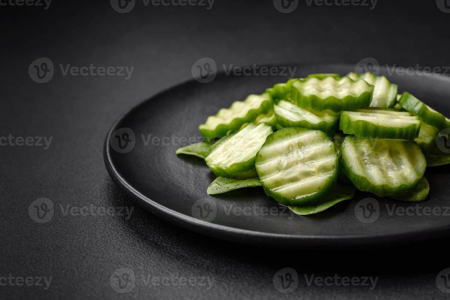 Delicious healthy raw cucumber sliced  on a black ceramic plate photo