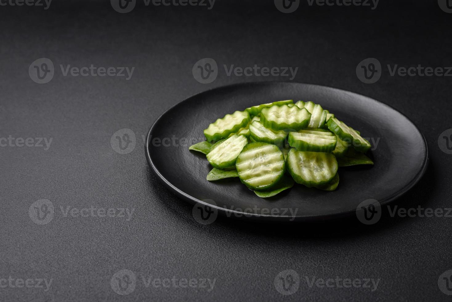 Delicious healthy raw cucumber sliced  on a black ceramic plate photo
