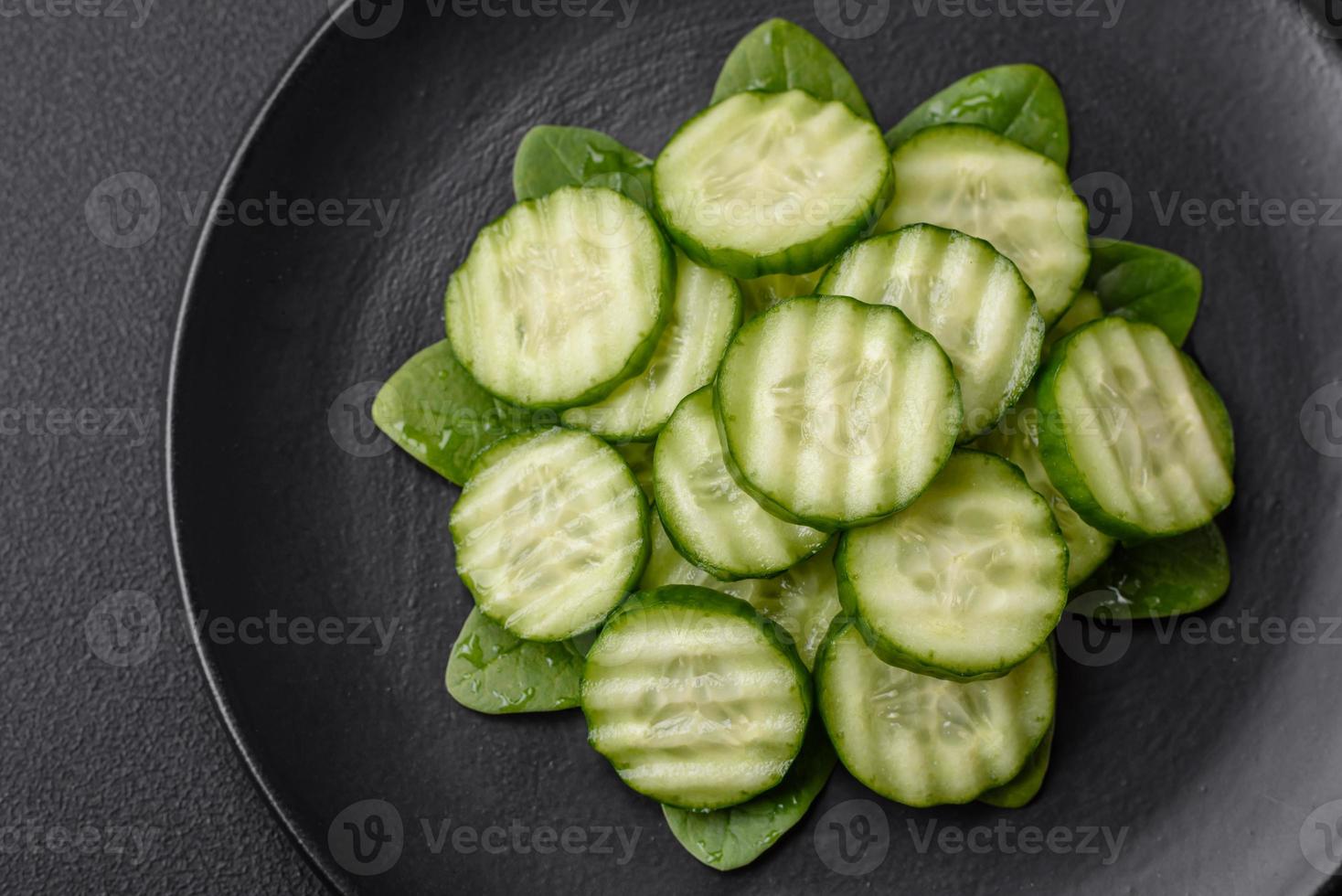 Delicious healthy raw cucumber sliced  on a black ceramic plate photo